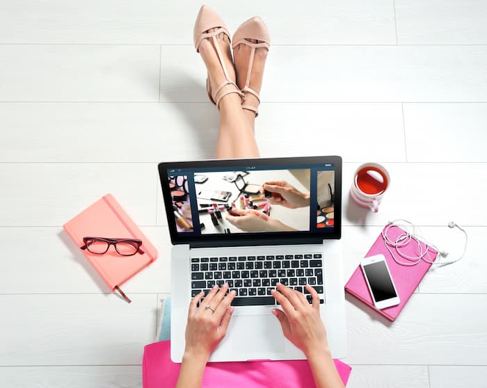 伸ばした脚の上にPCを置いておしゃれなランディングページを見ている女性